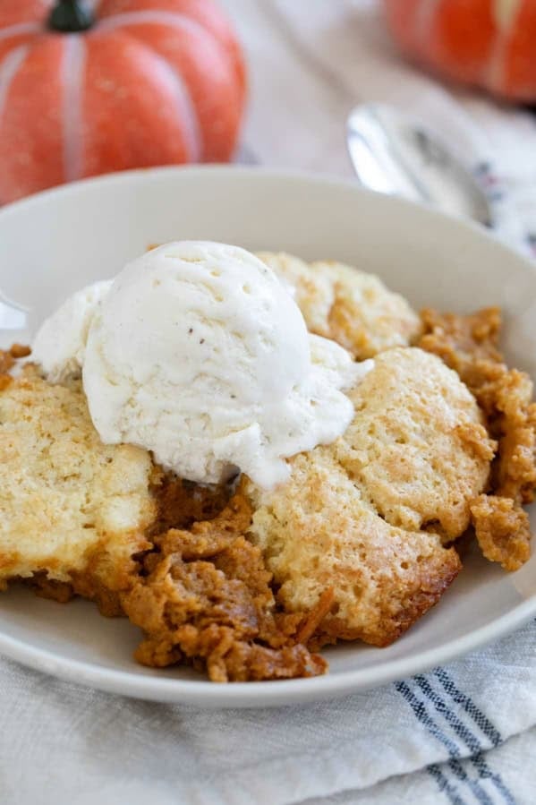 Serving of Pumpkin Cobbler in a bowl topped with vanilla ice cream.