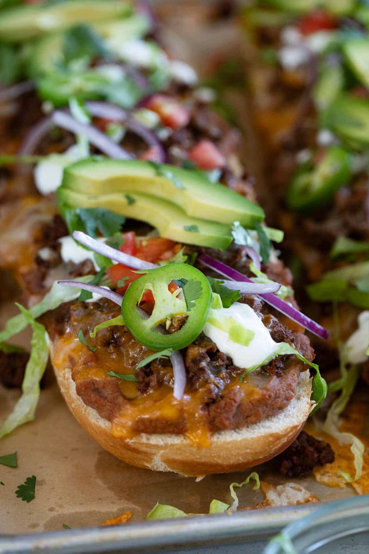 Taco French Bread Pizza with refried beans, taco seasoned meat, and lots of toppings.